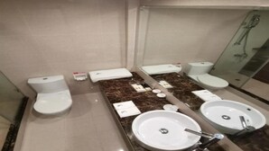 A modern bathroom with two toilets, a sink, and a shower. - Hong Kong Cosco Hotel (Hong Kong)