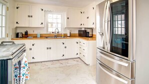 Une cuisine moderne avec des armoires blanches, des appareils en acier inoxydable et un sol en marbre.