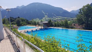 A swimming pool with diving boards and a small building, surrounded by lush greenery and mountains in the background. - Family-friendly 3-room vacation apartment with alpine views in Pfronten Mitte (Pfronten)
