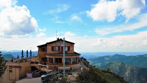 A rustic mountain lodge with a wooden exterior, a balcony with outdoor seating, and a view of the surrounding mountains. - Family-friendly 3-room vacation apartment with alpine views in Pfronten Mitte (Pfronten)