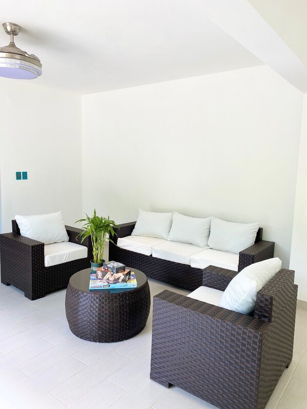 A modern living room with a sectional sofa, two armchairs, a coffee table, and a ceiling fan. - The White Rock Hotel BB (Guayacanes)