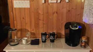Estación de café y té con fondo de madera, una cafetera, dos tazas, un hervidor de té y una tetera.