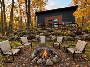 A modern house with a fire pit and outdoor seating.