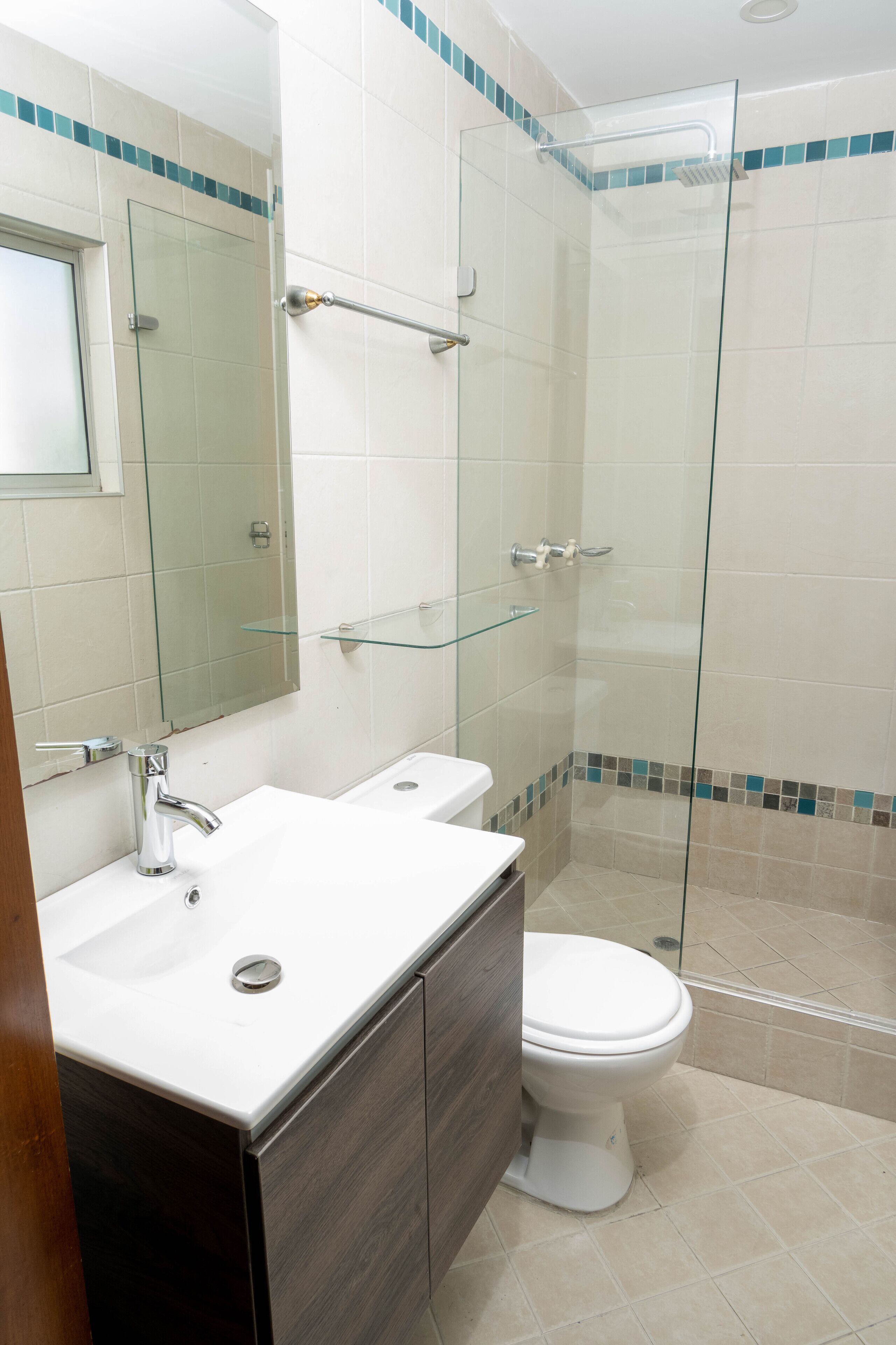 Une salle de bain avec deux lavabos, des toilettes, une douche à parois de verre et un miroir.