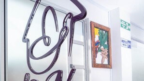 Une enseigne pour «La Nona Casa Boutique», avec un motif de maison stylisé et le nom écrit en caractères cursifs.
