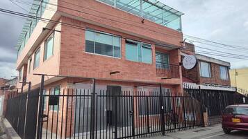 Um edifício de dois andares com fachada de tijolos, janelas grandes e cerca de metal preto.