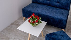Un salon moderne avec un canapé bleu, une table basse blanche et un arrangement floral.