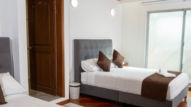 Une chambre d’hôtel moderne dotée d’un grand lit, d’un lit plus petit et d’un espace salon séparé.