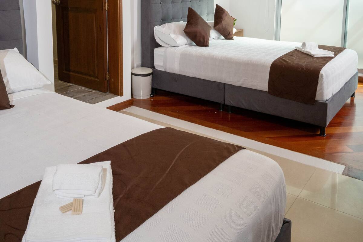 A modern hotel room with a large bed, a smaller bed, and a separate seating area.