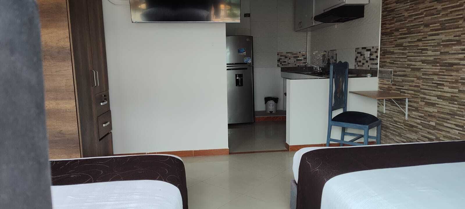 Una habitación compacta con kitchenette, una cama y una silla.