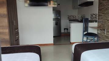 Una habitación compacta con kitchenette, una cama y una silla.