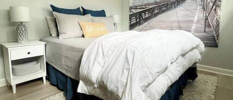 A bedroom with a bed, nightstand, and a large window with a view of a bridge.