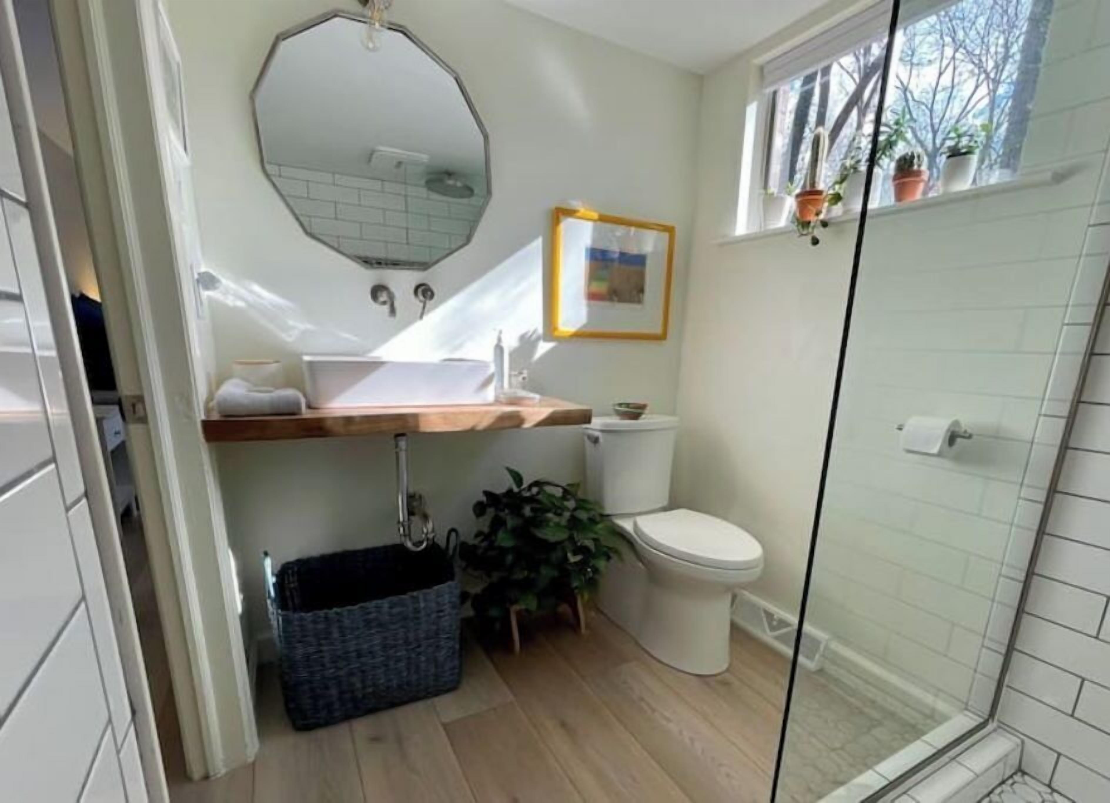 Un baño con tocador de madera, un lavabo blanco, un inodoro y una zona de ducha.