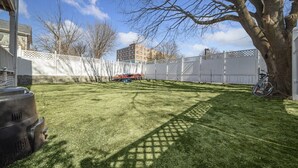 A well-maintained backyard with a lawn, a tree, and a white fence.