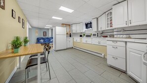 A modern kitchen with white cabinets, a wooden dining table, and a blue patterned rug.
