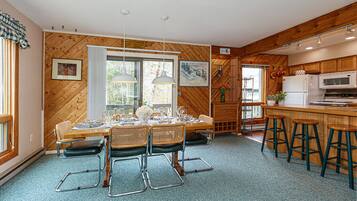 Un coin repas avec une table en bois dressée pour six personnes, entourée de chaises en osier.