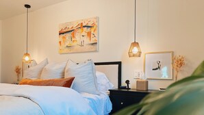 Une chambre à coucher avec un lit, des tables de chevet, un tableau et une lampe.