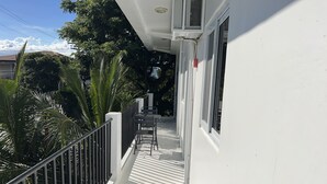 Een wit gebouw met een balkon, een zwart hekwerk en een raam.