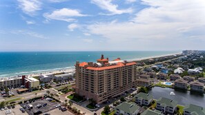 Un hotel de gran altura con techo rojo, cerca de una playa y una masa de agua.