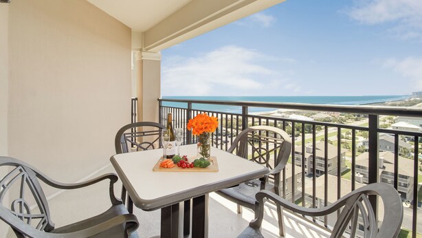 Ein Balkon mit Tisch für zwei Personen, komplett mit einer Weinflasche, Gläsern und einem Blumenarrangement.