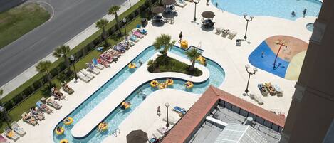 A large outdoor swimming pool with multiple lanes, sun loungers, and umbrellas.