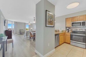 A modern kitchen with stainless steel appliances, wooden cabinets, and a dining area with a view.