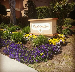 A registration sign surrounded by colorful flower beds.