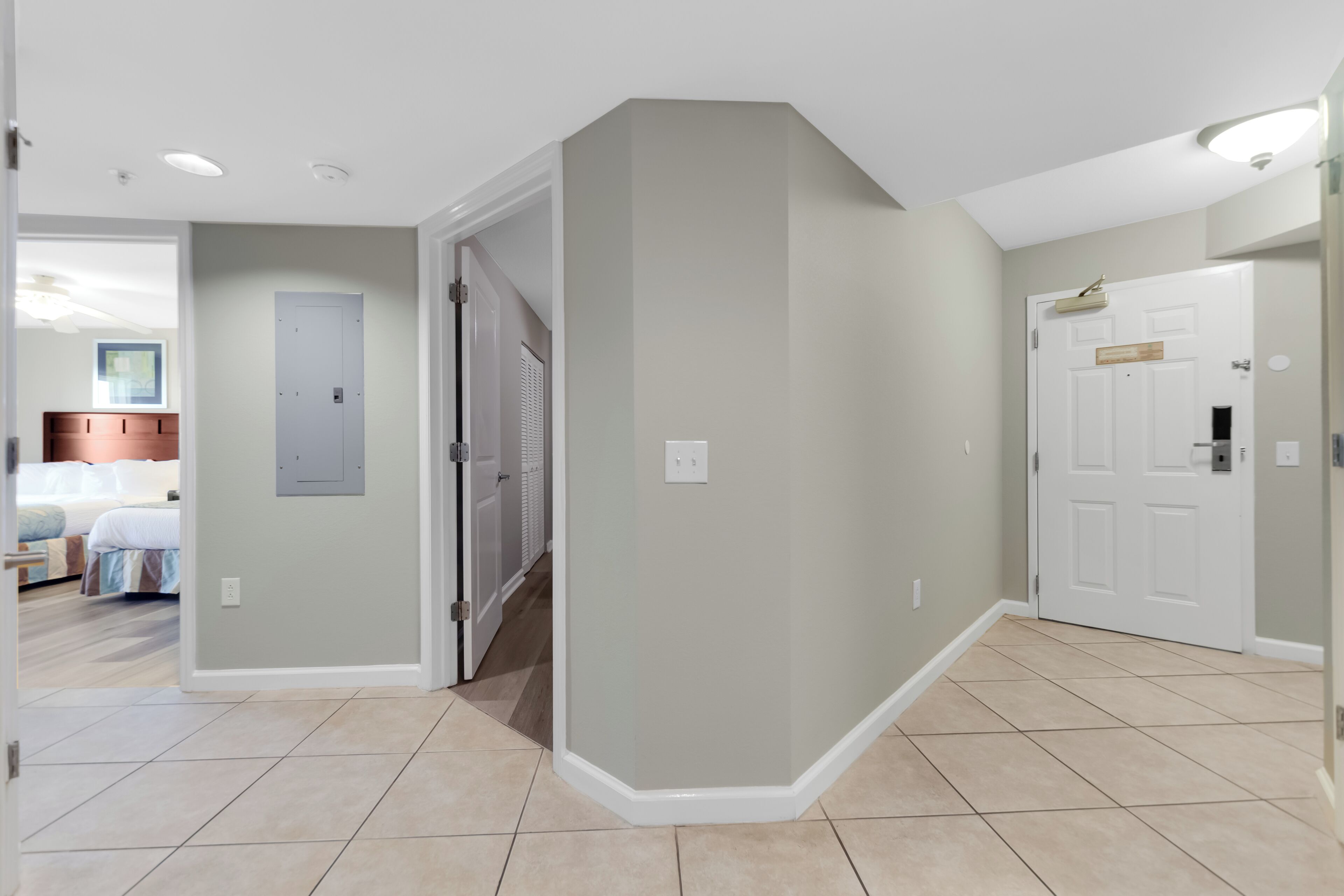 A hallway with a door leading to a bedroom, a light switch, and a door with a mailbox.