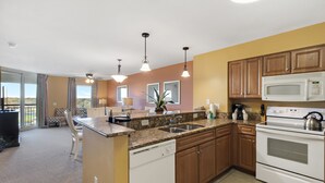 A kitchen with granite countertops, wooden cabinets, a dishwasher, a stove, and a microwave.