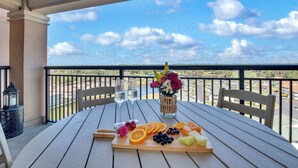 Ein Tisch mit Obstplatte, Gläsern und Blumen am Balkon mit Blick auf die Landschaft.