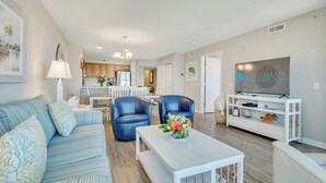 Un salon moderne comprenant un canapé, deux fauteuils, une table basse et un téléviseur.