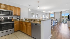 A modern kitchen with wooden cabinets, stainless steel appliances, granite countertops, and pendant lighting. - 3BR- 5th floor- Lake & Golf View condo|Short walk to beach| Resort Access| (North Myrtle Beach)