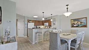A kitchen with wooden cabinets, a white refrigerator, and a dining area with a table and chairs. - 3BR- 6th floor- Lake & Golf View condo|Short walk to beach| Resort Access| (North Myrtle Beach)