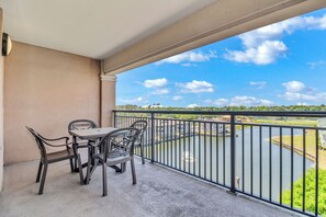 Een balkon met een tafel en stoelen, met uitzicht op een rivier en groen.