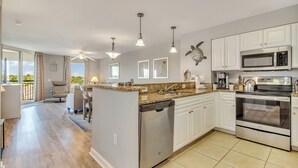 A modern kitchen with white cabinets, stainless steel appliances, and a central island with a dishwasher. - 3BR- 7th floor- Lake & Golf View condo|Short walk to beach| Free parking (North Myrtle Beach)