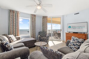 A spacious living room with a large window, a ceiling fan, and a television on a wooden cabinet.