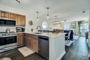 Une cuisine moderne avec des meubles en bois, des appareils électroménagers en acier inoxydable et des luminaires suspendus.