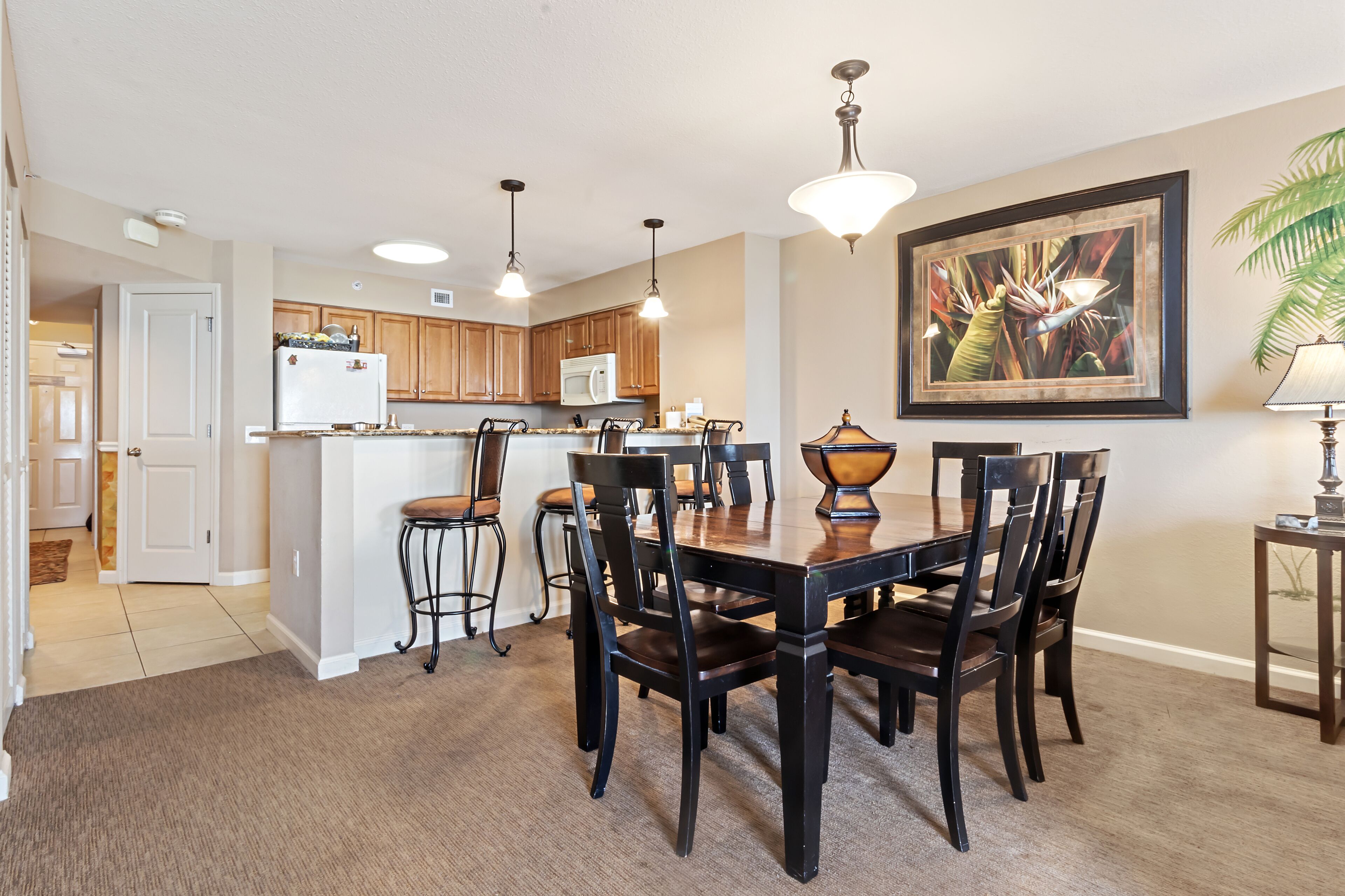 A modern kitchen with wooden cabinets, a central island, and pendant lighting.