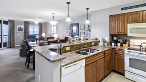 Eine moderne Küche mit Granit Arbeitsplatten, Edelstahlgeräten und Holzschränken.