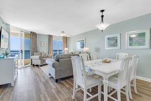 Cozy living area with a dining table for four, ceiling fan, and ocean views from the balcony.