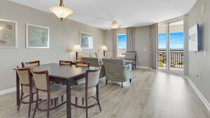 Une pièce spacieuse comprenant une table à manger, des chaises et offrant une vue sur l’océan grâce à de grandes fenêtres.