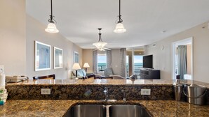 Cozinha moderna com bancadas de granito, pia de aço inoxidável e iluminação pendente.