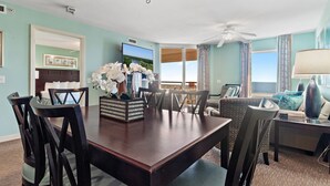A dining area with a wooden table, chairs, and a vase of white flowers.