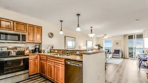 A modern kitchen with wooden cabinets, stainless steel appliances, and a granite countertop. - 3BR- 8th floor- Oceanview condo| Short walk to beach| Resort Access| (North Myrtle Beach)
