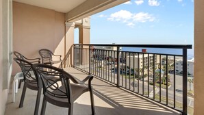 A balcony with a table and chairs, overlooking a street and buildings.