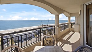 Ein Balkon mit Blick auf den Strand und das Meer, ausgestattet mit einem Tisch und Stühlen.