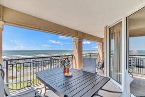 Un balcon avec une table, des chaises et un vase rempli de fleurs.