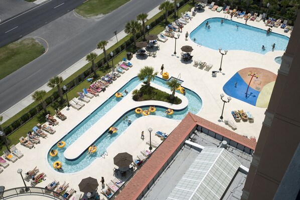 A large outdoor swimming pool with multiple lanes, sun loungers, and umbrellas.