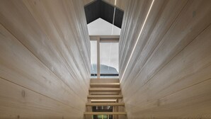 A modern interior with a wooden staircase leading to a large window, offering a view of the outdoors.