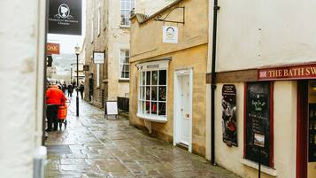 A narrow street with shops, including a patisserie and a chocolate shop.